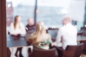 Ihmisiä neuvotteluhuoneessa lasiseinän takaa katsottuna